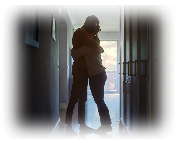 A couple holding each other close in the light of a doorway